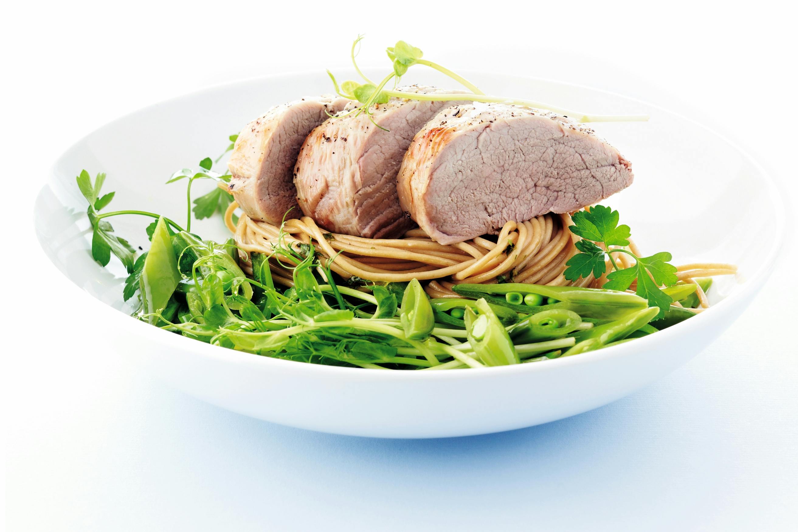 Pastaa, porsaanfilettä ja versosalaattia lautasella