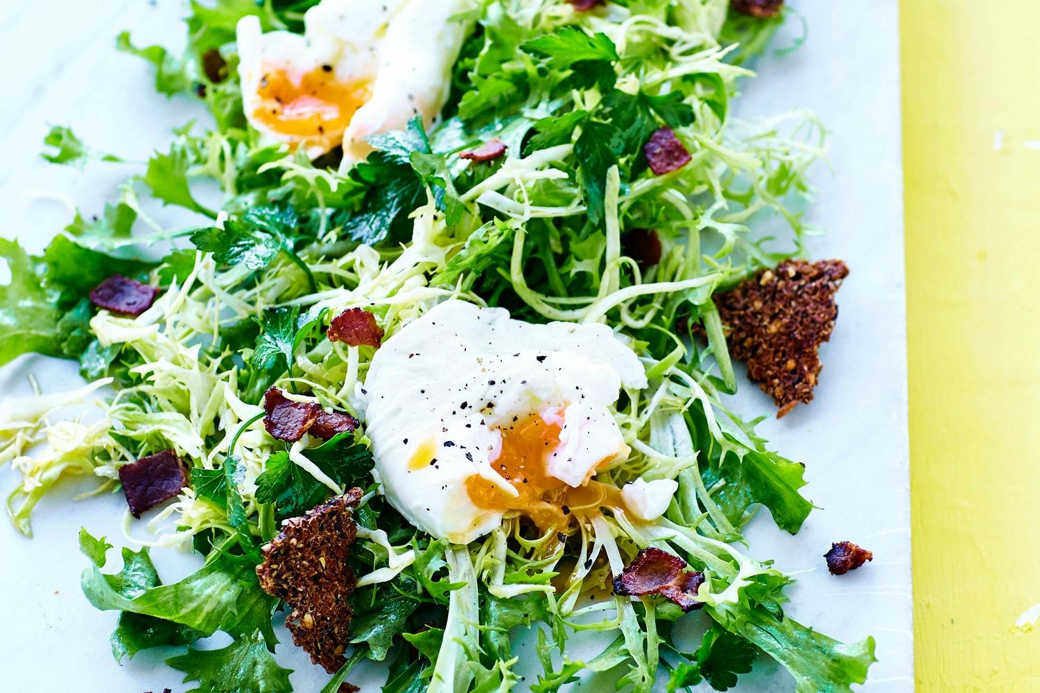 Posjert egg, salat og rugbrødchips på marmorplate