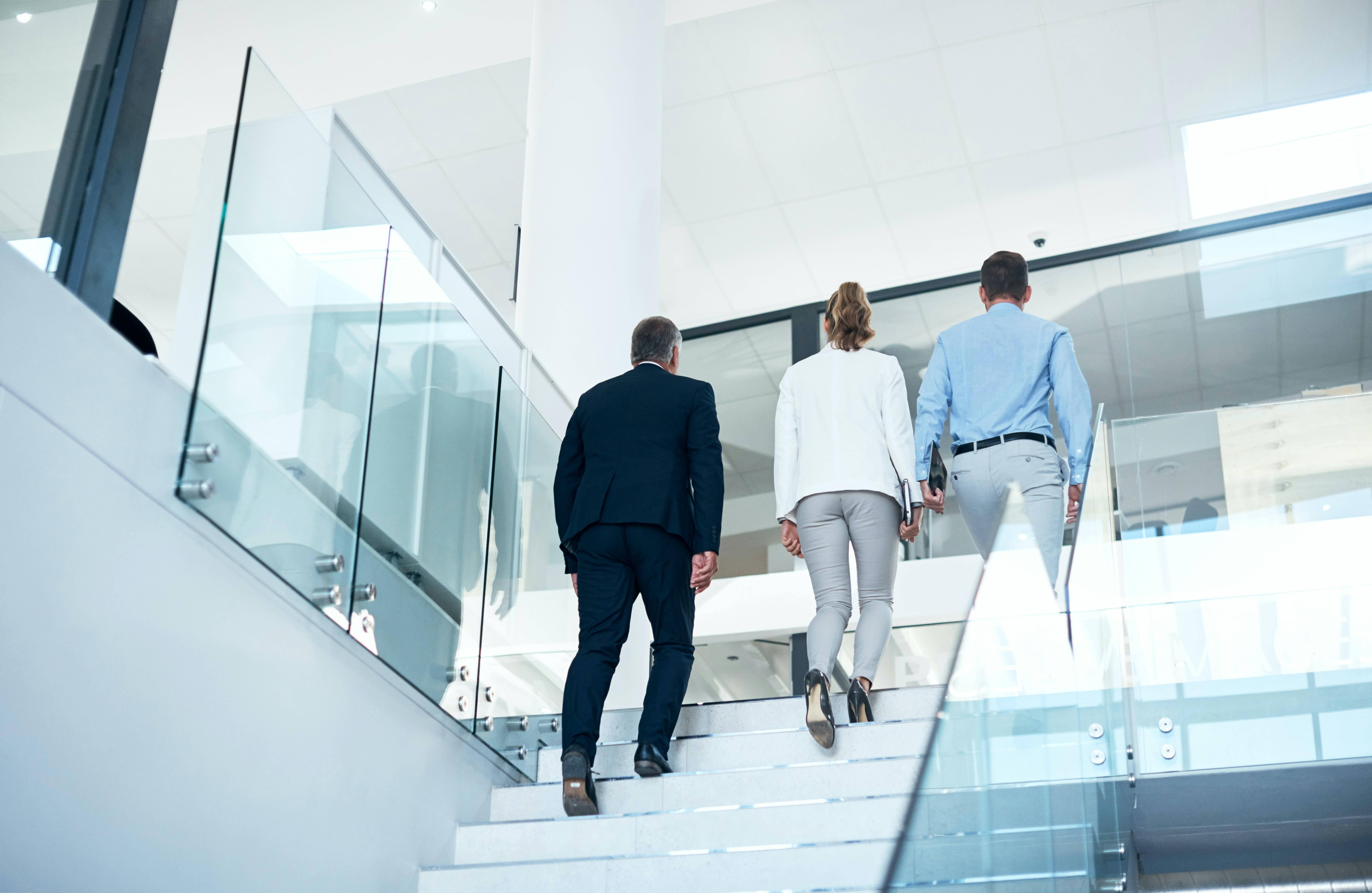 Två män och en kvinna går i trappor