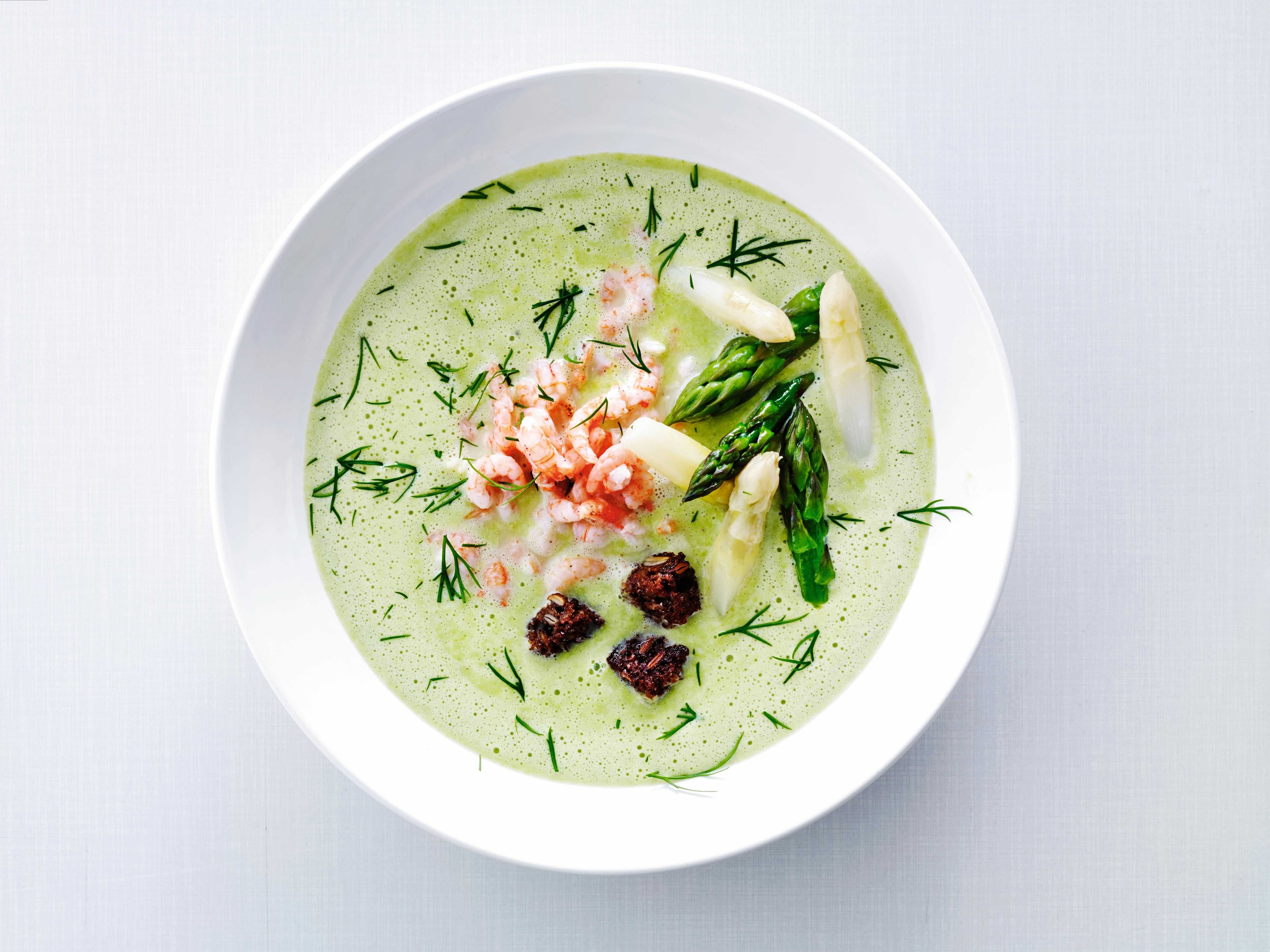 Dyp tallerken med grønn suppe toppet med reker