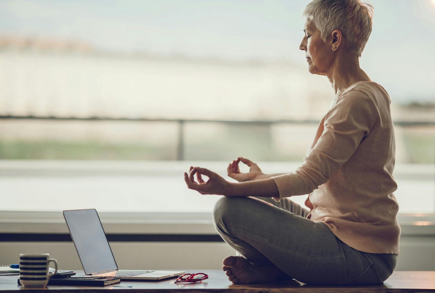 Nainen meditoi tietokoneen ääressä