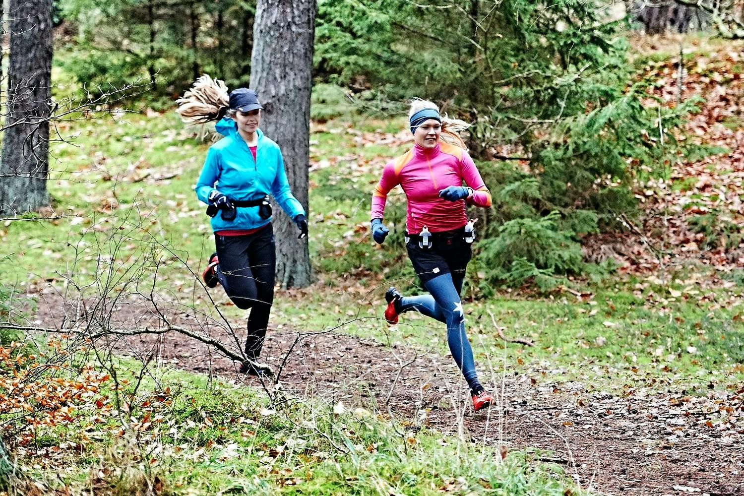 To kvinner trener terrengløping i skogen