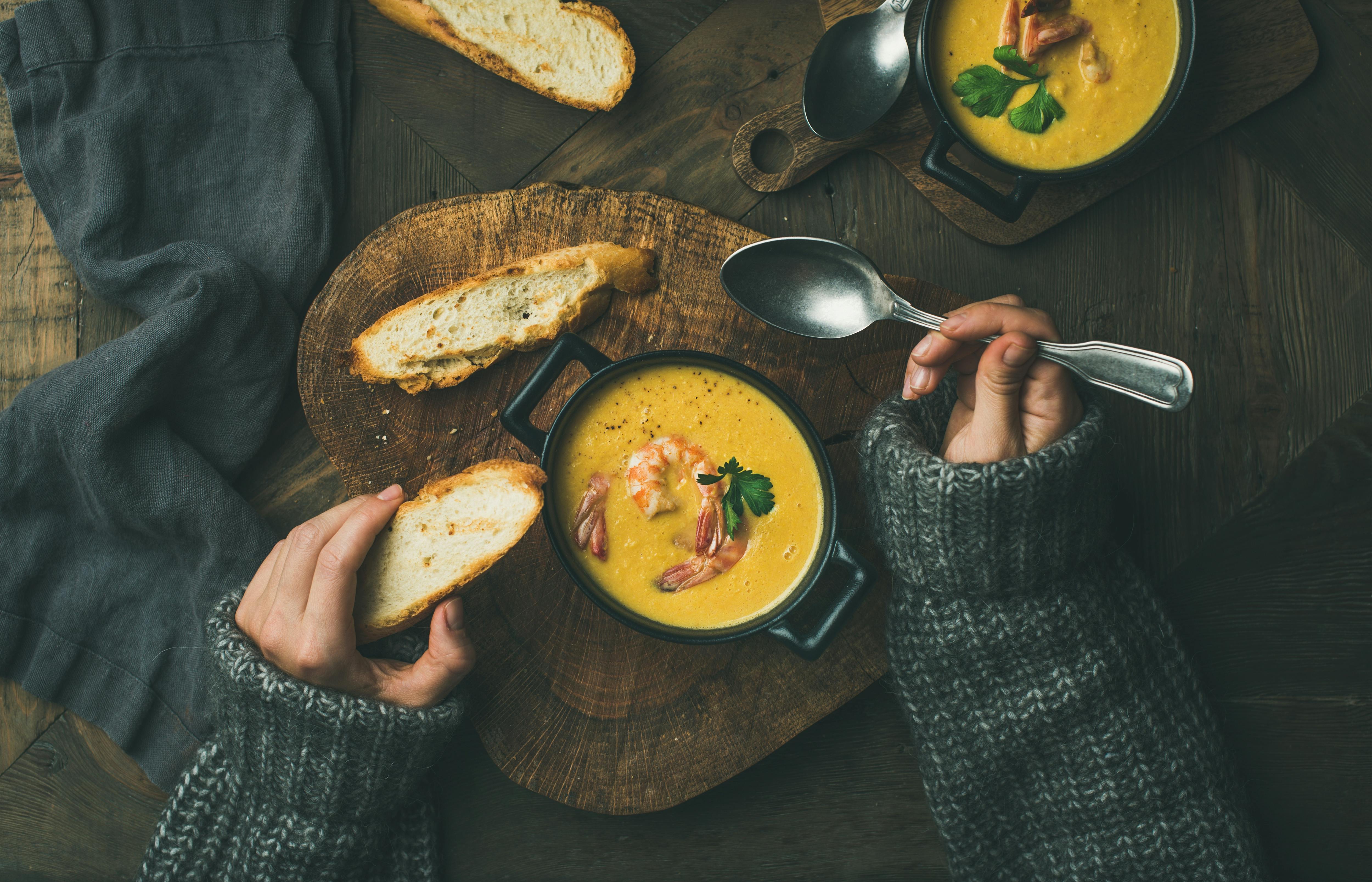Kvinde spiser grøntsagssuppe med rejer