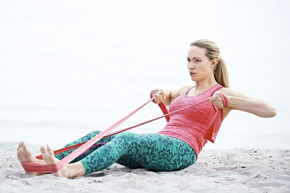 Kvinde laver styrketræning med træningselastik