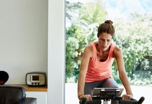 Kvinna på motionscykel hemma