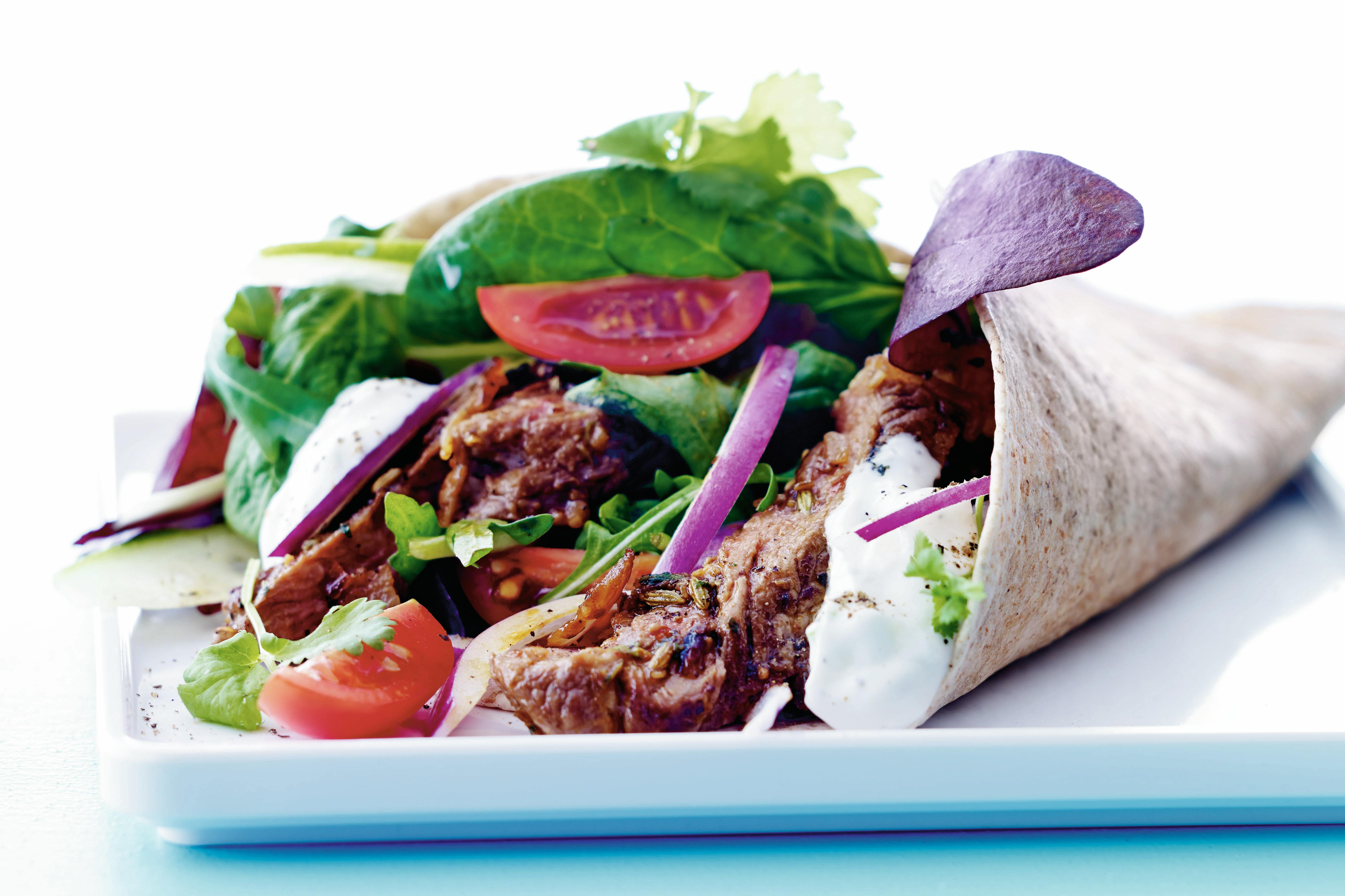Tallrik med tunnbröd, nötkött, tomat, sallad, rödlök och dressing