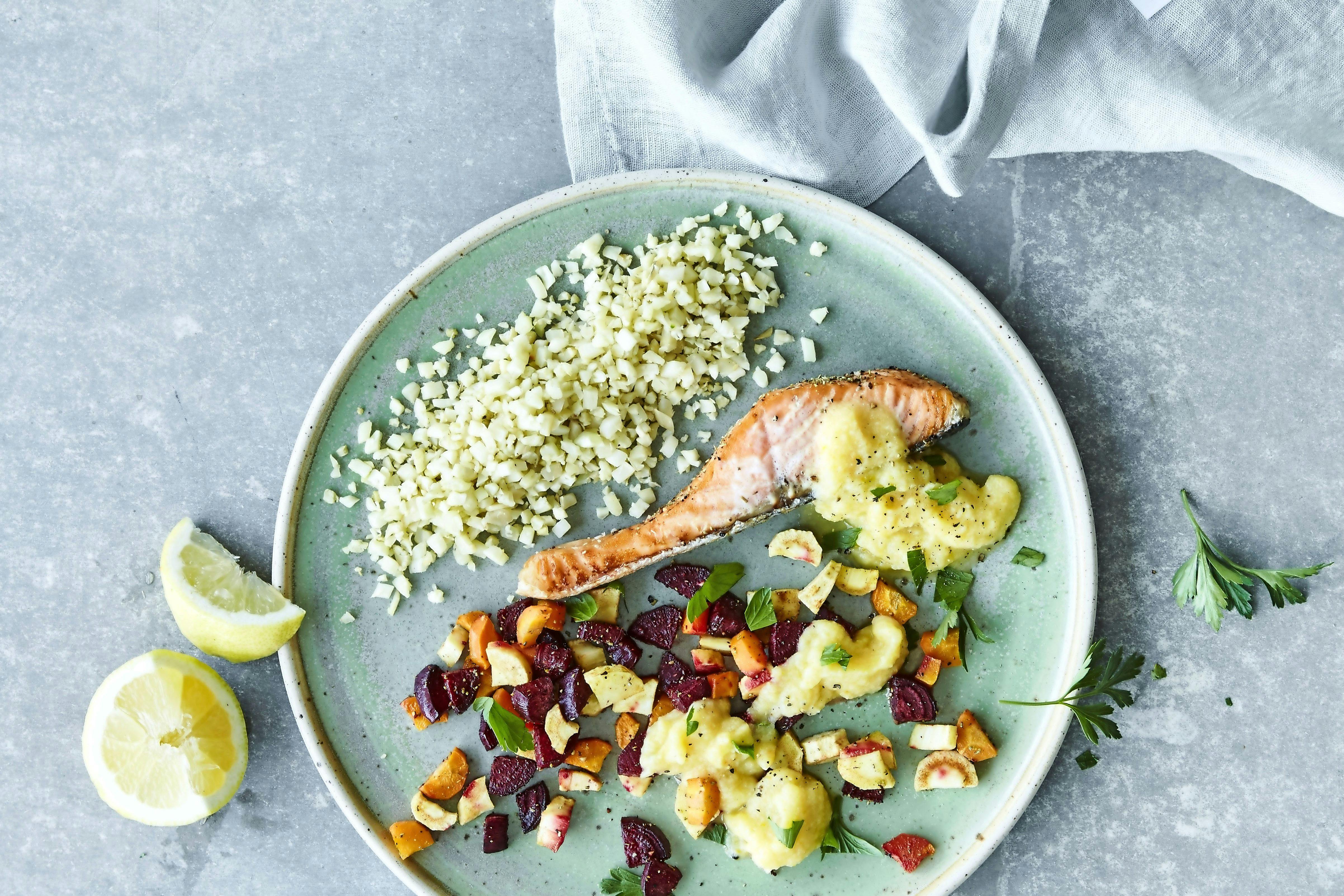 Tallrik med lax, blomkålsris, rotfrukter och sås