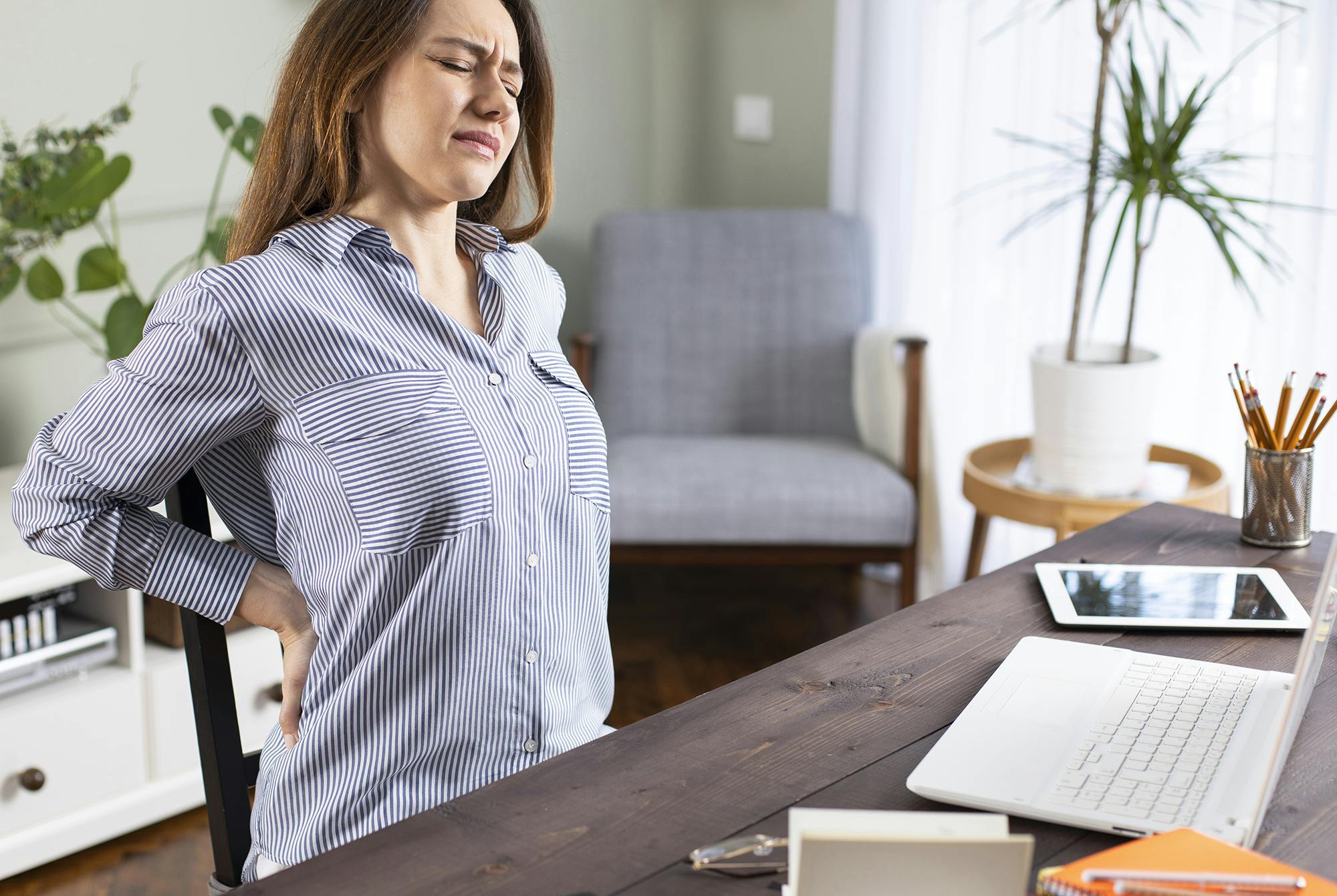 Kvinde med ondt i ryggen på hjemmekontor