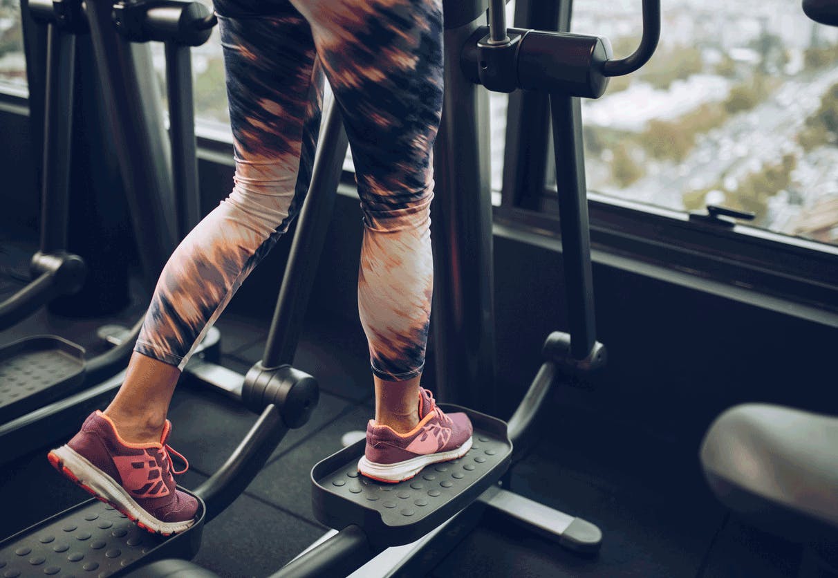 kvinna värmer upp på crosstrainer