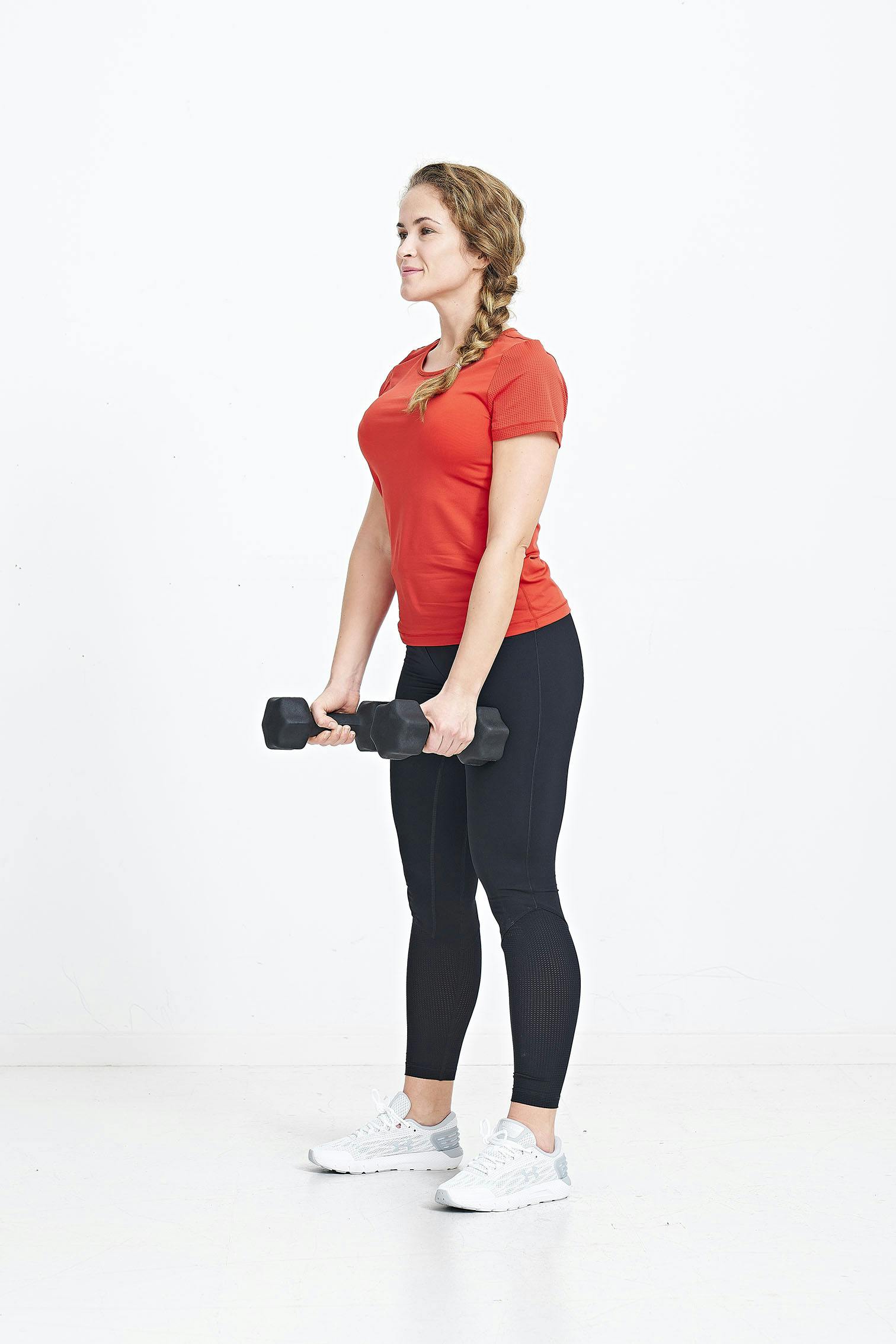 Nainen seisoo käsipainot käsissä.