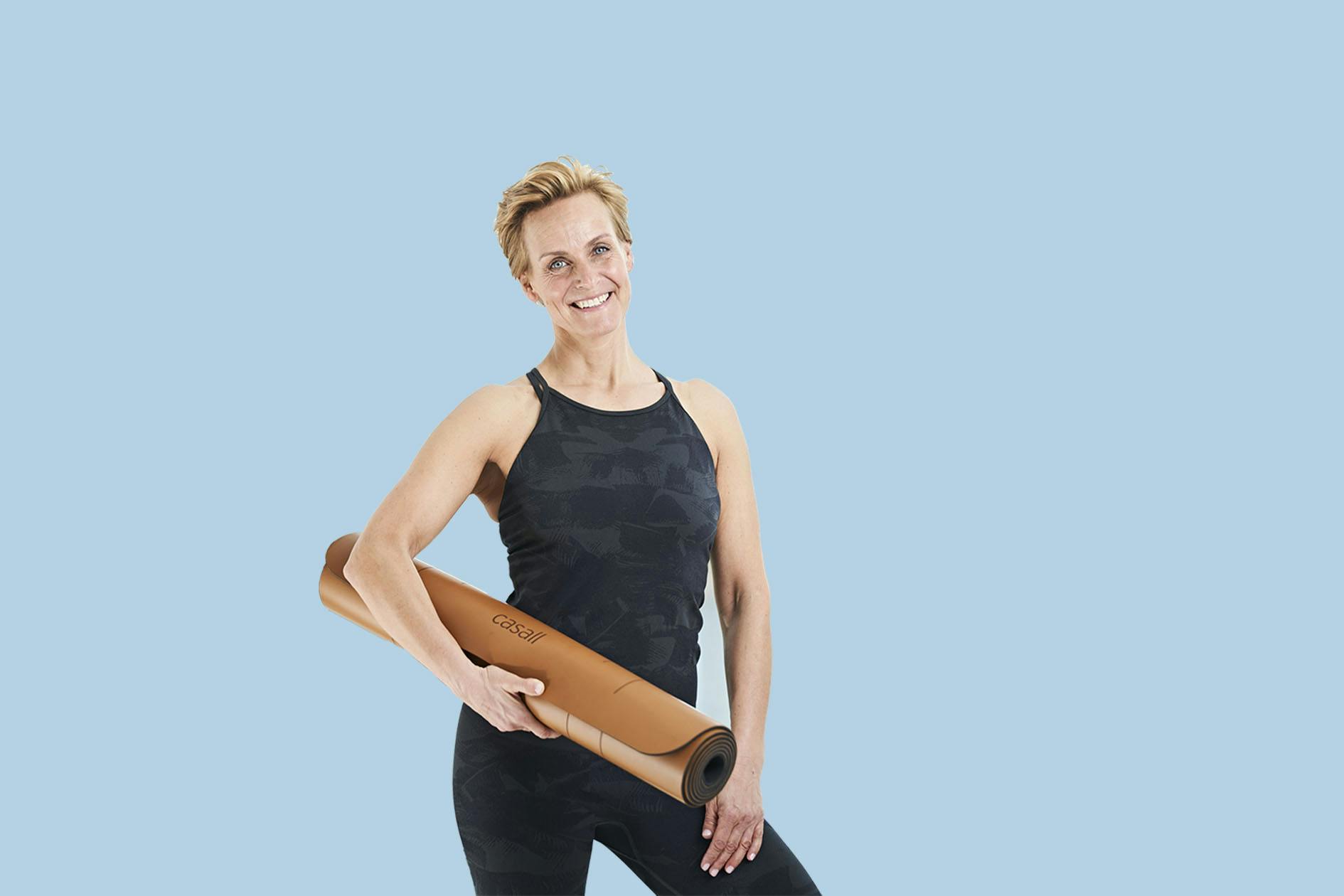 Kvinne står med yogamatte