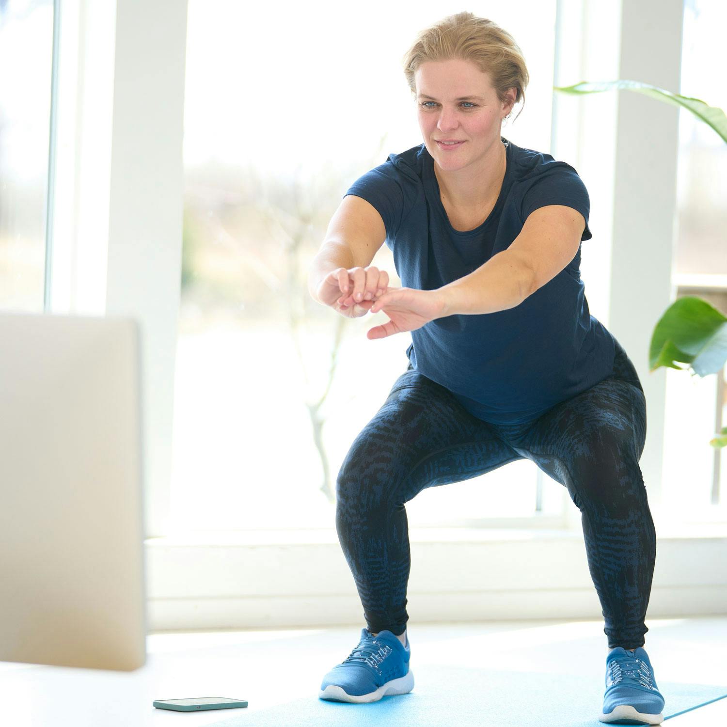 Kvinna tränar med träningsvideo hemma