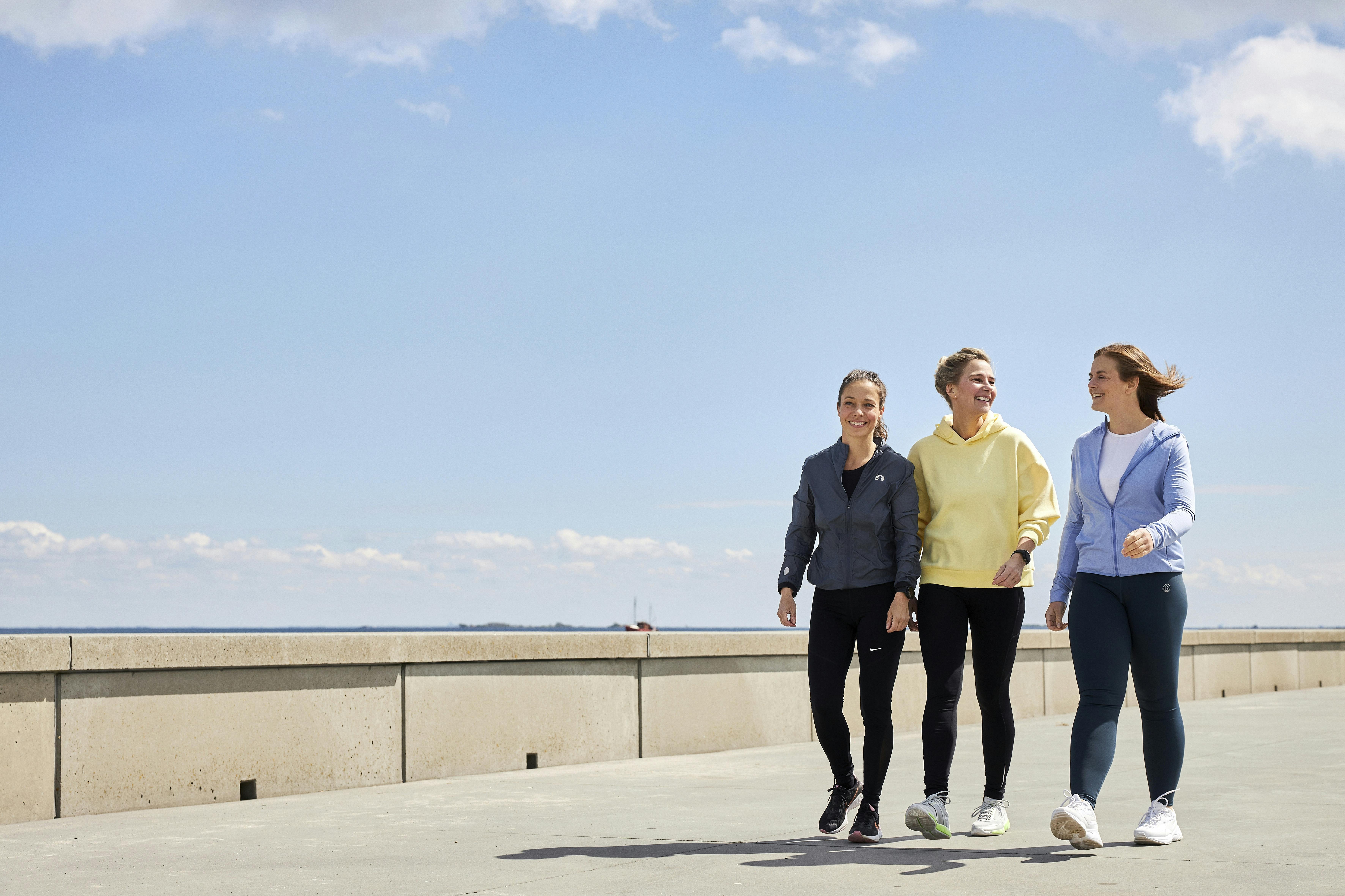 Naiset kävelevät rannalla