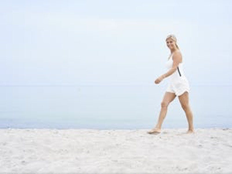 Nainen kävelee hiekkarannalla