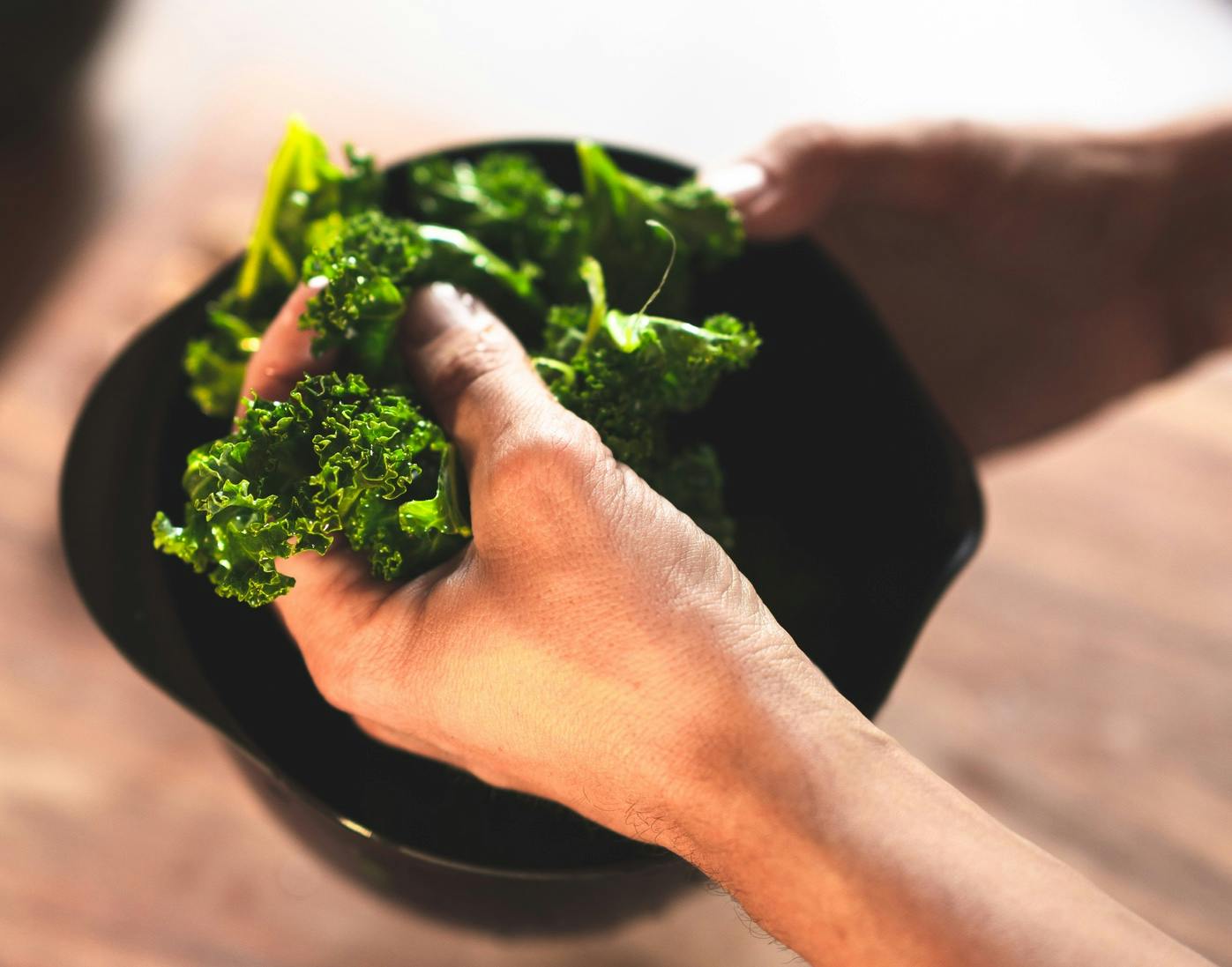 Käsi kääntelee lehtikaalia kulhossa