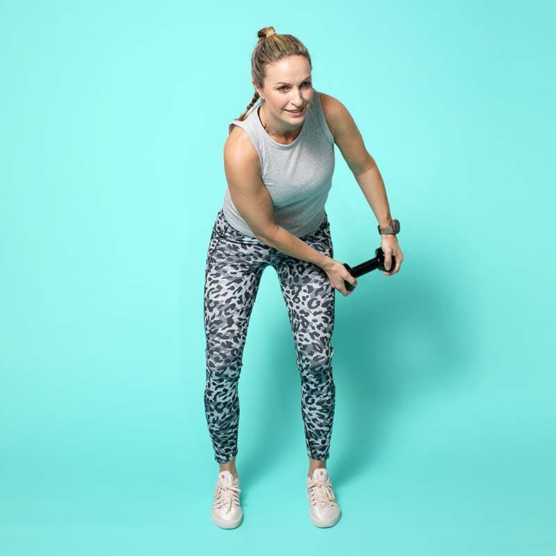 Kvinna i träningskläder som svingar en hantel