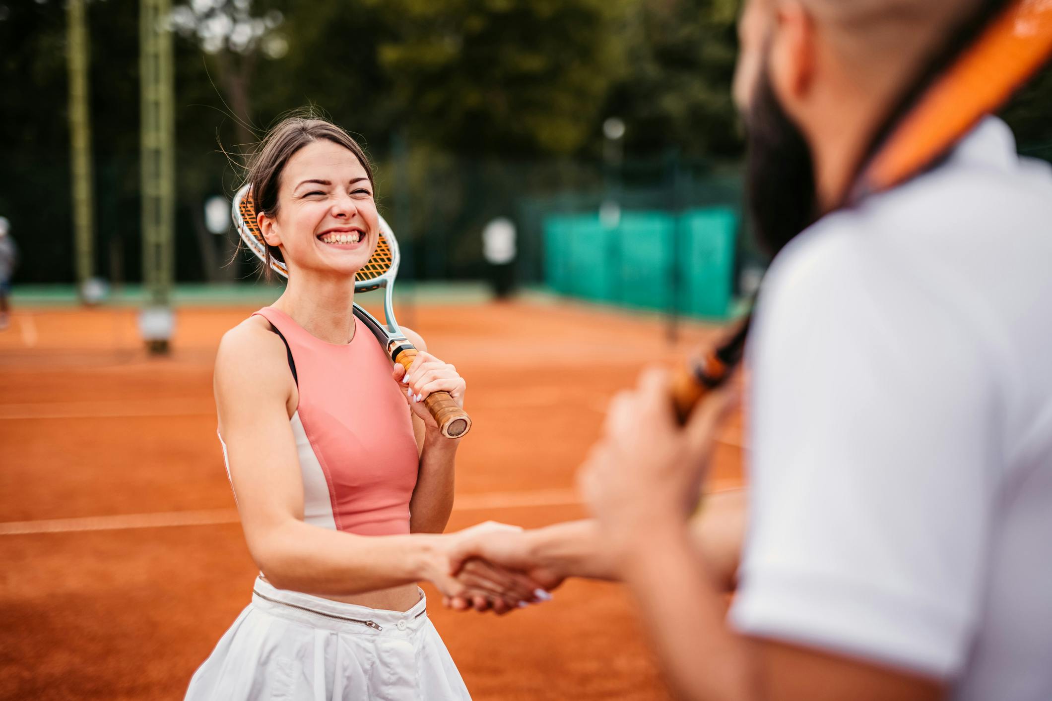 Billede af kvinde, der spiller tennis og smiler.