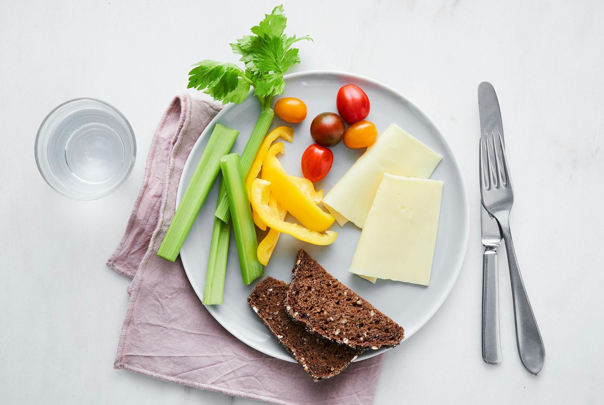 Tallerken med rugbrød, ost, stangselleri, tomat og paprika