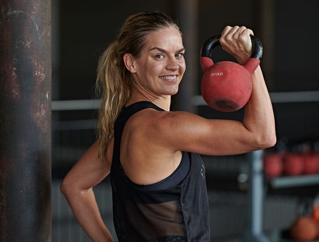 Kvinde med kettlebel i fitnesscenter
