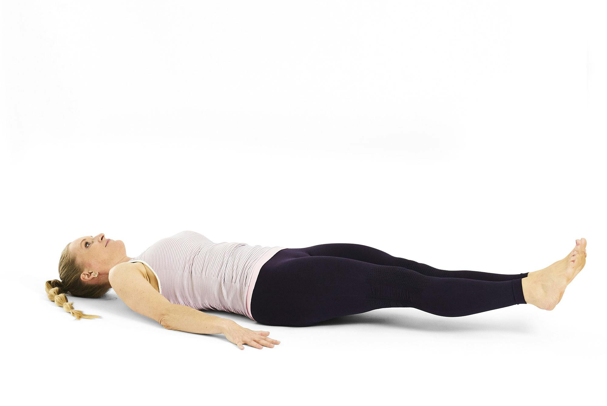 Nainen tekee harjoitetta jalkojen nosto makuulla