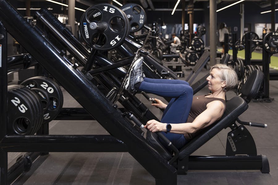 Kvinne i beinpress med maskin på treningssenter