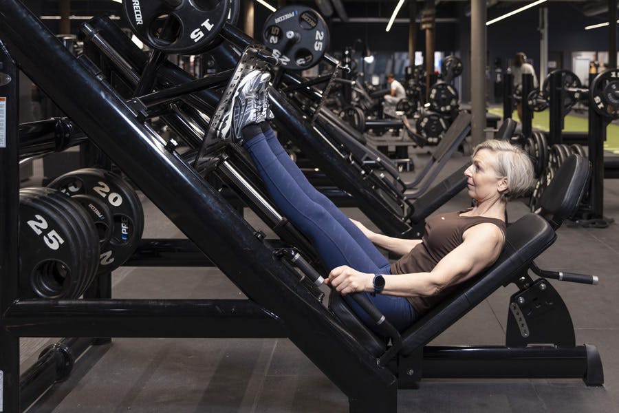 Kvinne i beinpress med maskin på treningssenter