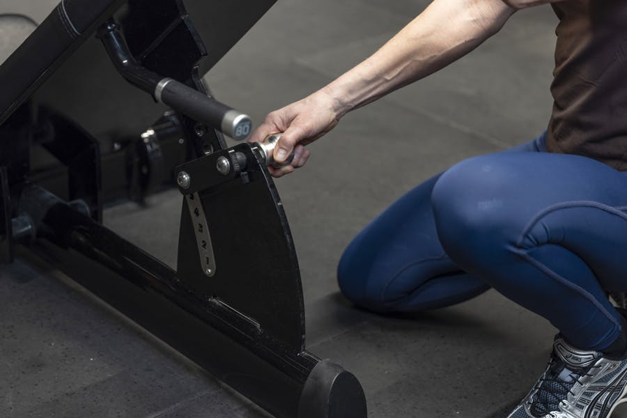 Kvinne justerer ryggstøtten på beinpressmaskinen