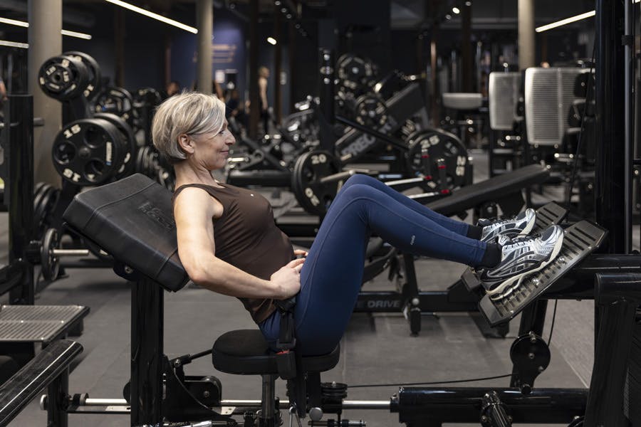 Kvinne gjør hofteskyv med maskin på treningssenter