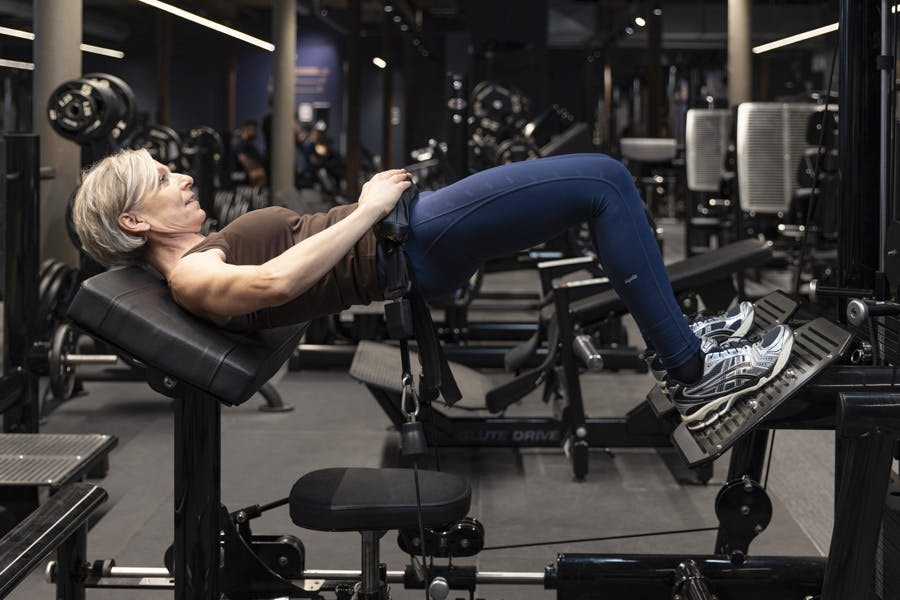 Kvinne gjør hofteskyv med maskin på treningssenter