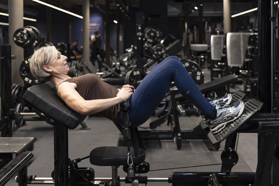 Kvinne gjør hofteskyv med maskin på treningssenter