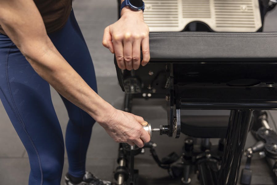 Kvinnehender justerer ryggstøtten på et treningsapparat