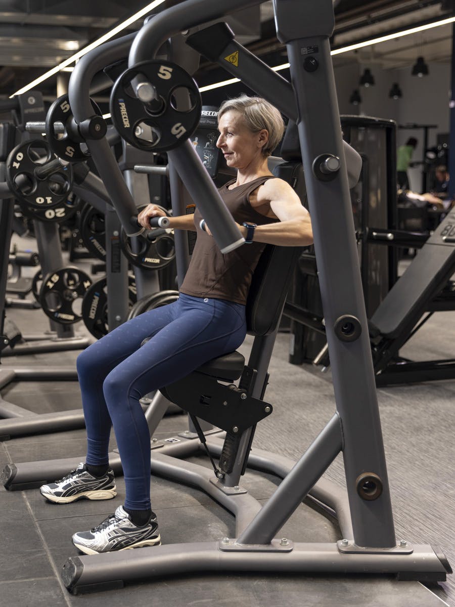 Kvinne gjør brystpress med maskin på treningssenter