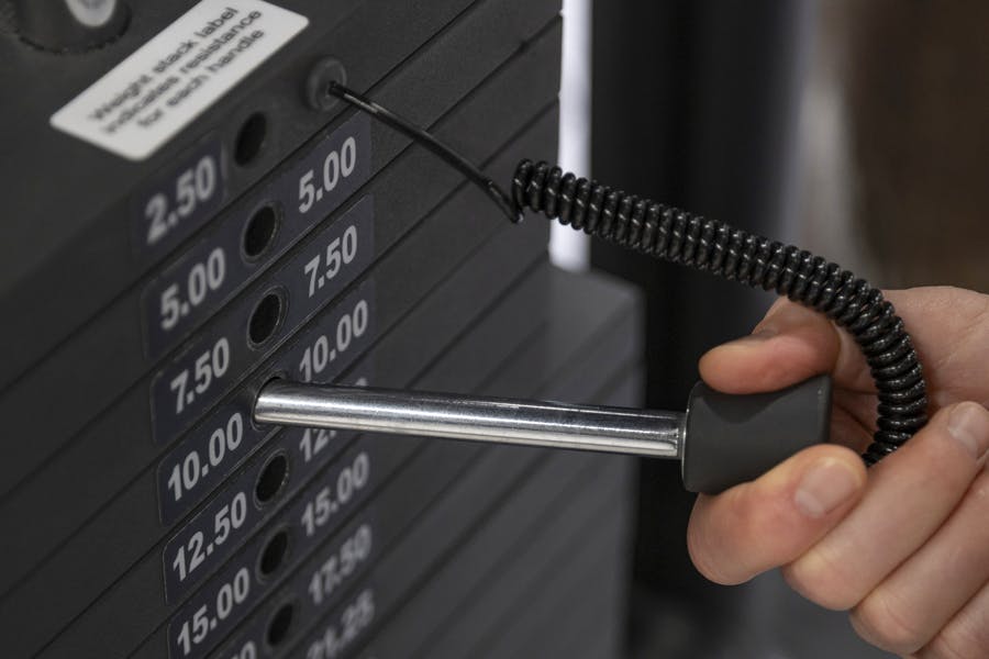 Kvinne setter vekt på styrketreningsmaskin