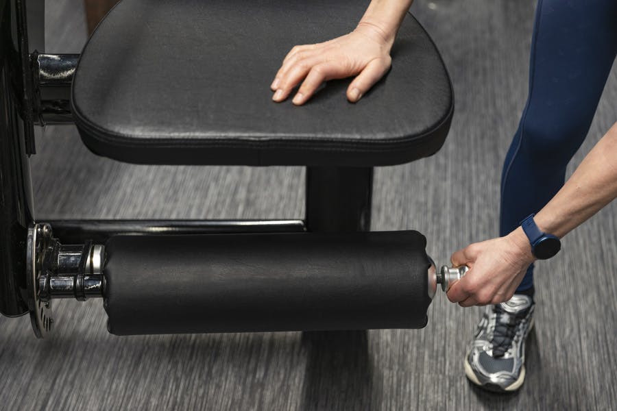 Kvinne justerer fotstøtten på et treningsapparat