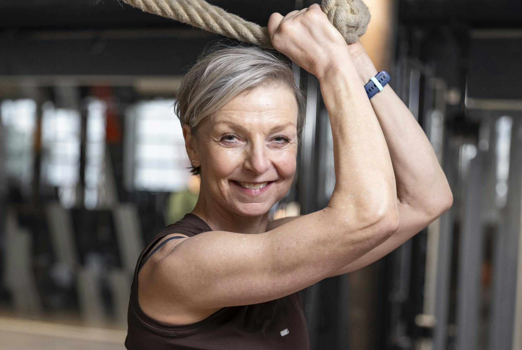 Leende kvinna håller i rep på gym