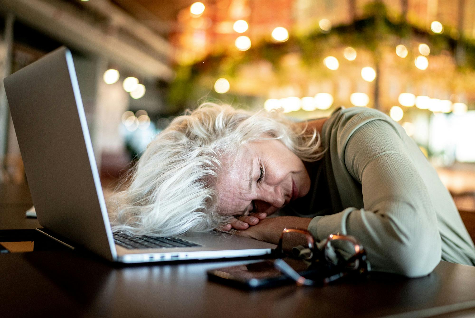 Medelålders kvinna ligger med huvudet på sin dator och har symtom på ADHD.
