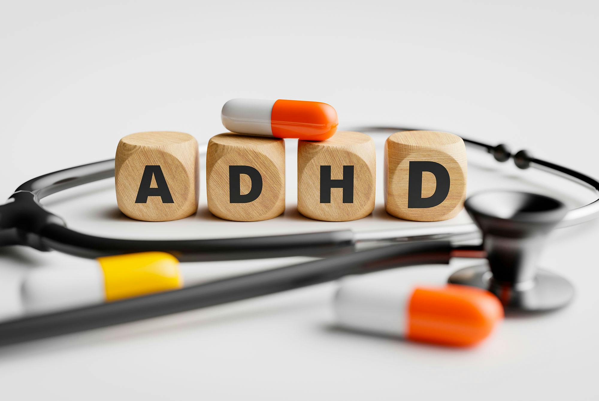 ADHD skrivet med versaler och omgivet av piller på ett bord.