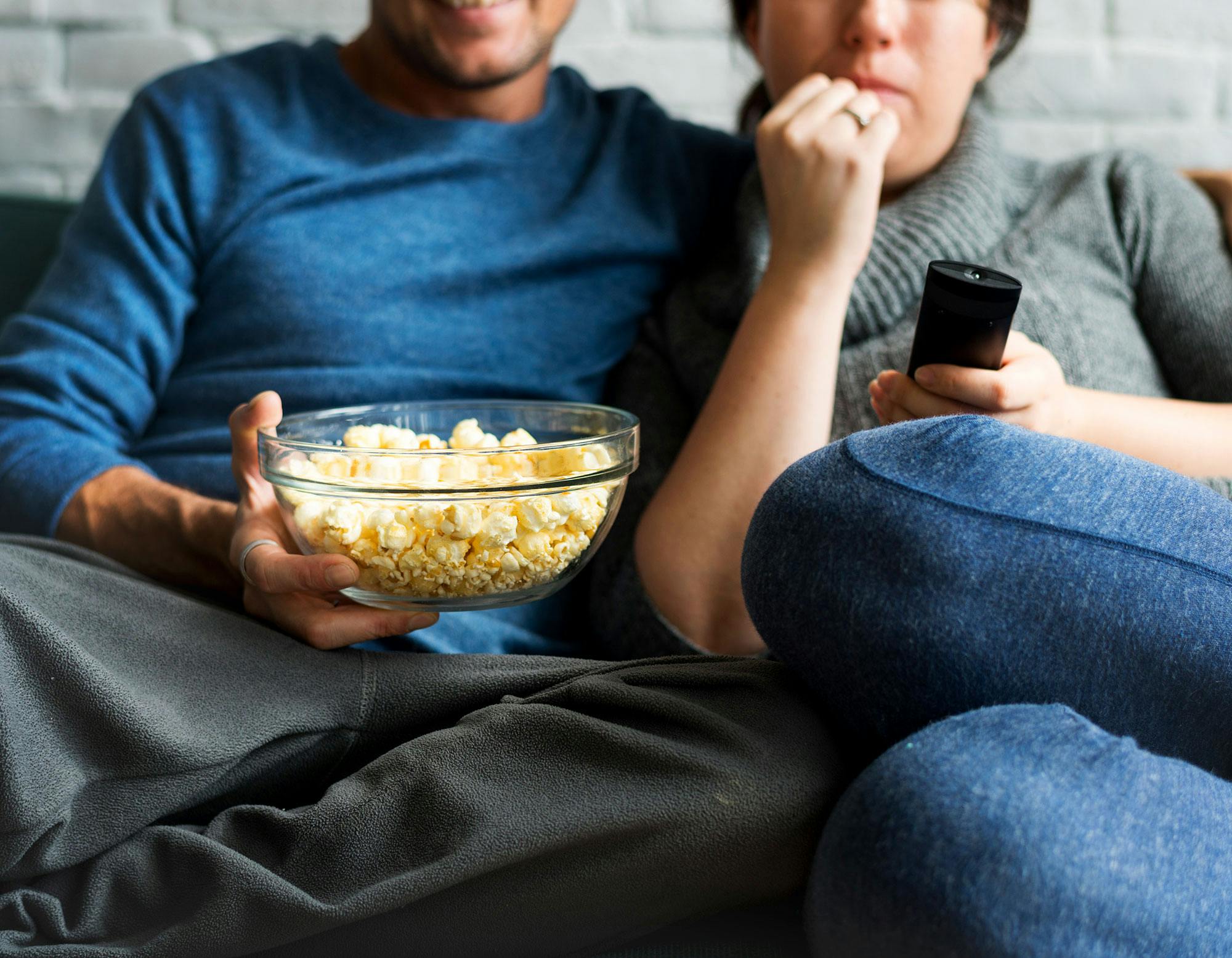 Et par spiser popcorn på sofaen. De vil gerne undgå mellemmåltider om aftenen.