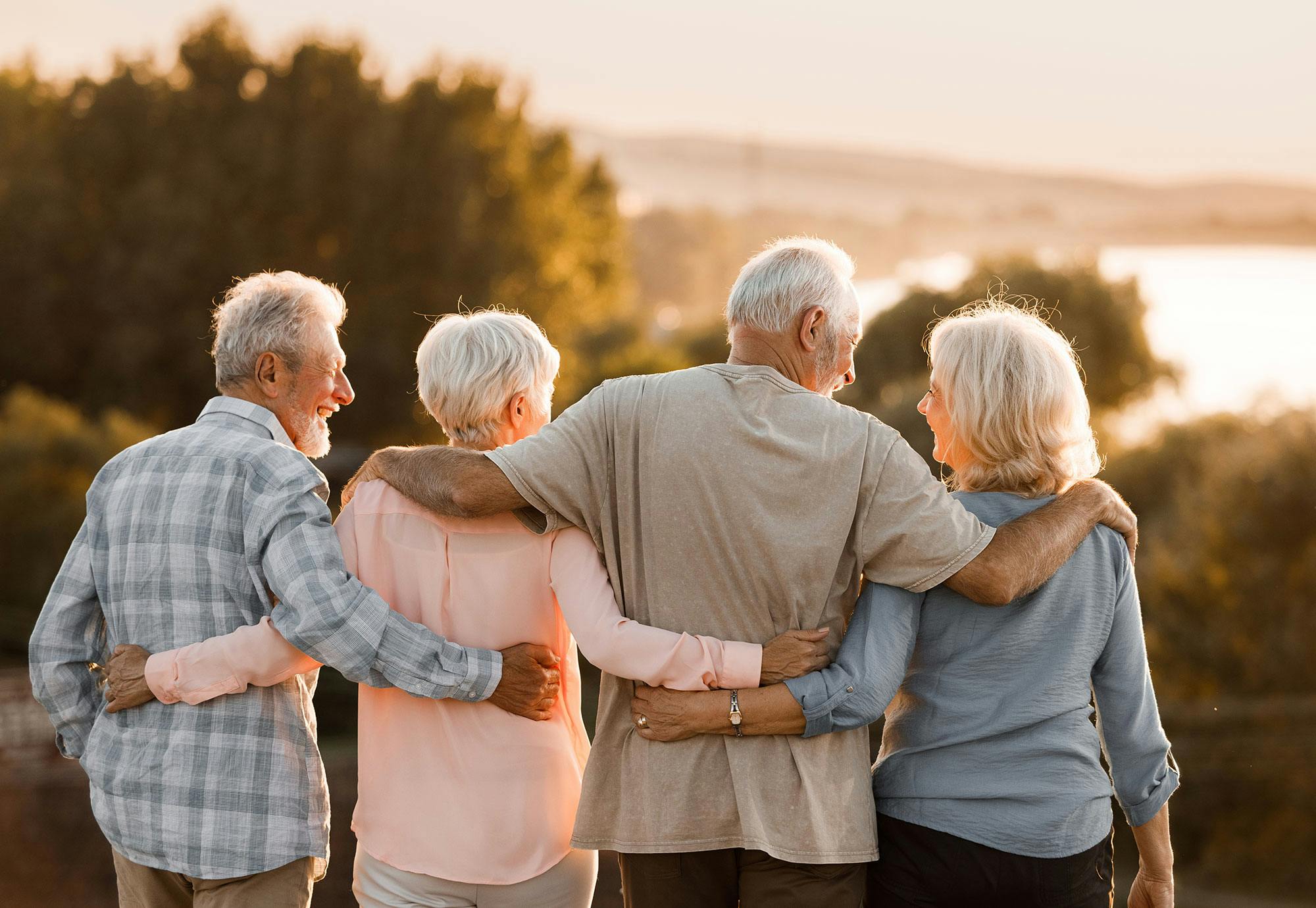 Fyra äldre personer står med ryggen mot naturen.