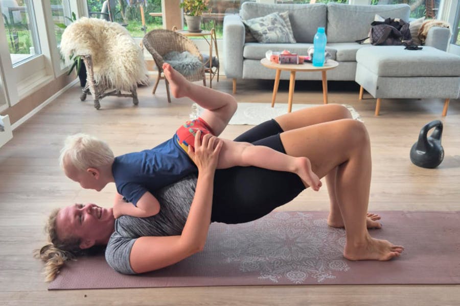 Kvinna som tränar på matta, barn som ligger på magen
