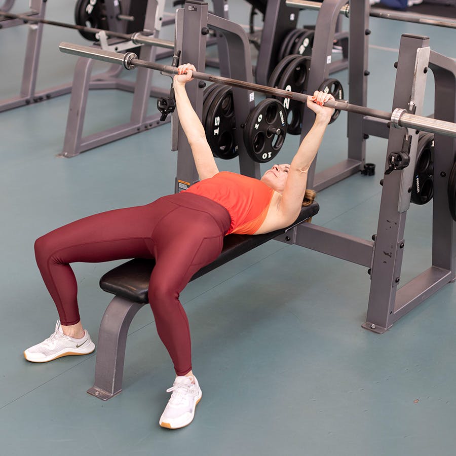 Lang vektstang løftet over hodet i benkpressøvelsen