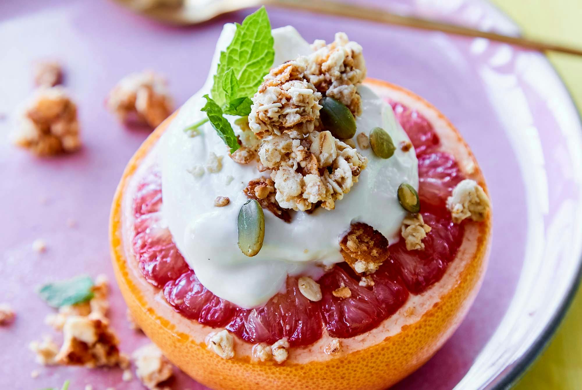 Puolikas greippi, jonka päällä jogurttia ja granolaa.