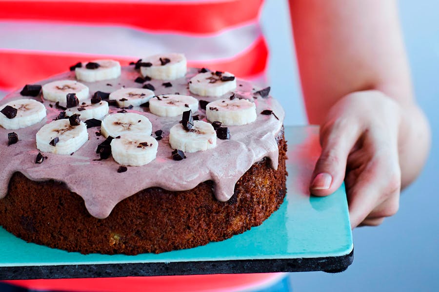 Kvinne holder banankake med kakaokrem og bananskiver