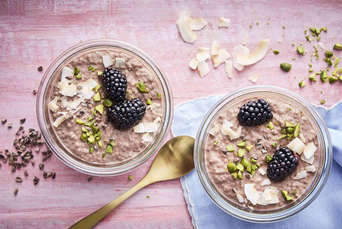 Kaakaonväristä, marjoilla koristeltua chiapuuroa kulhoissa.