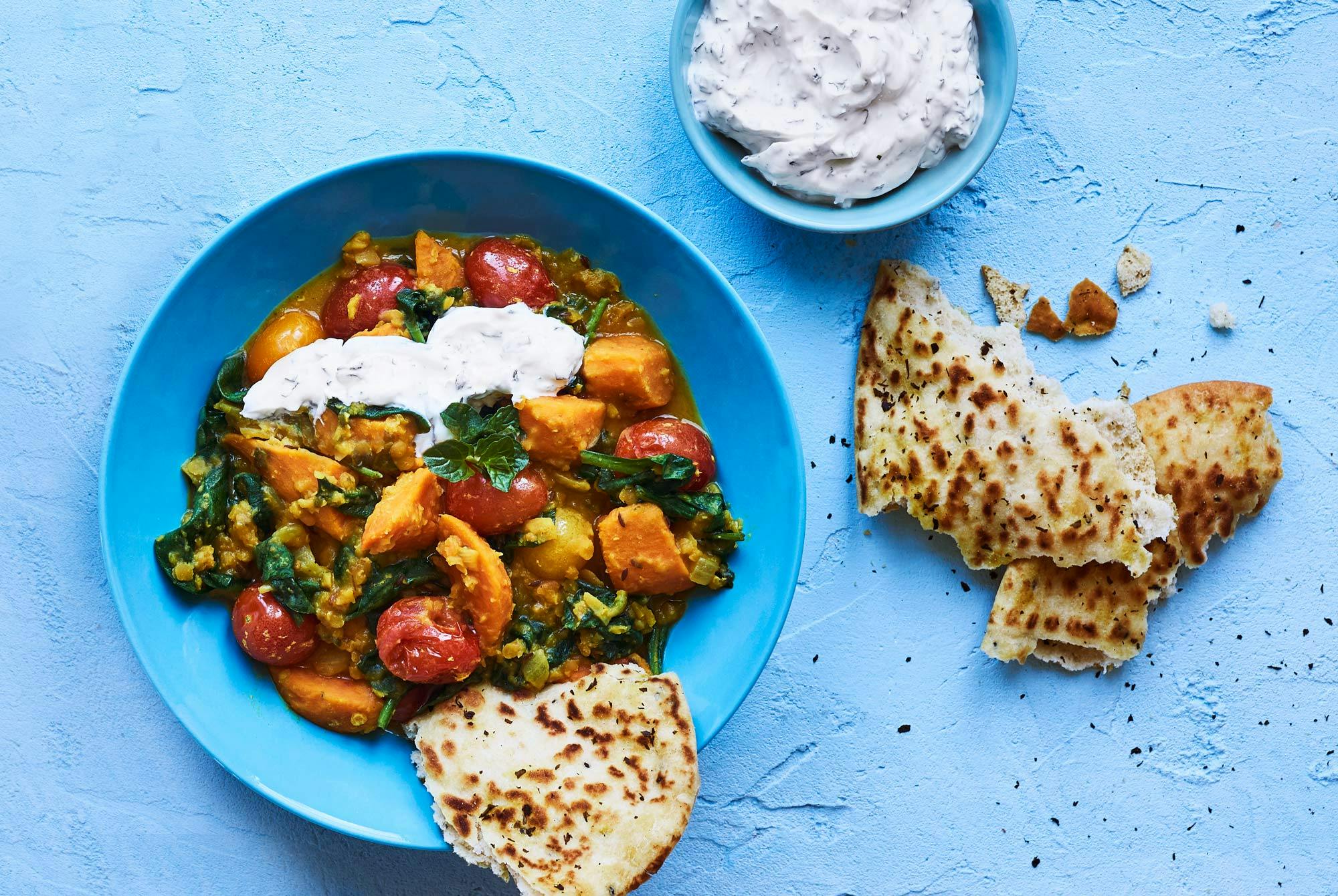 En porsjon dahl med røde linser, servert med naanbrød og raita