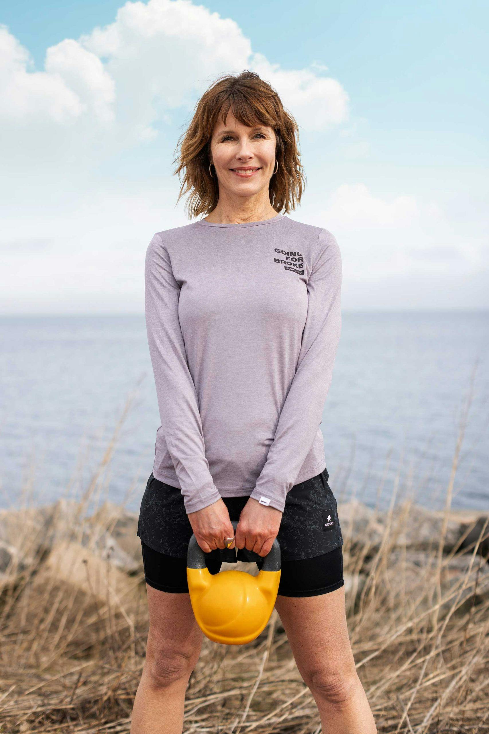 dame med kettlebell smiler i naturen