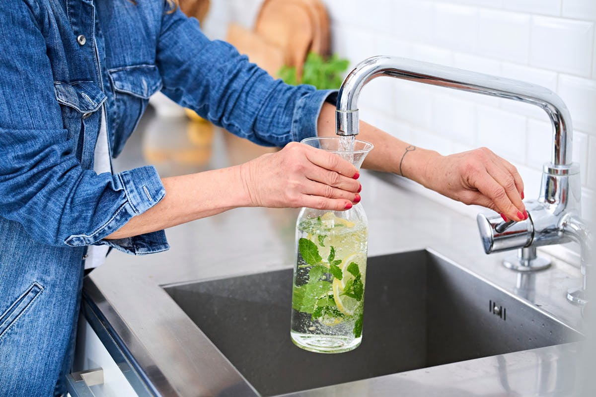 Kvinde fylder vand i en glaskande