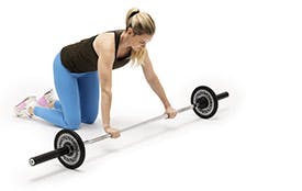 Kvinna gör ab roll-övningen med en skivstång
