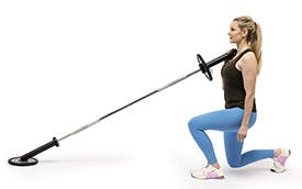 Kvinna som utför övningen back lunge till landmine press