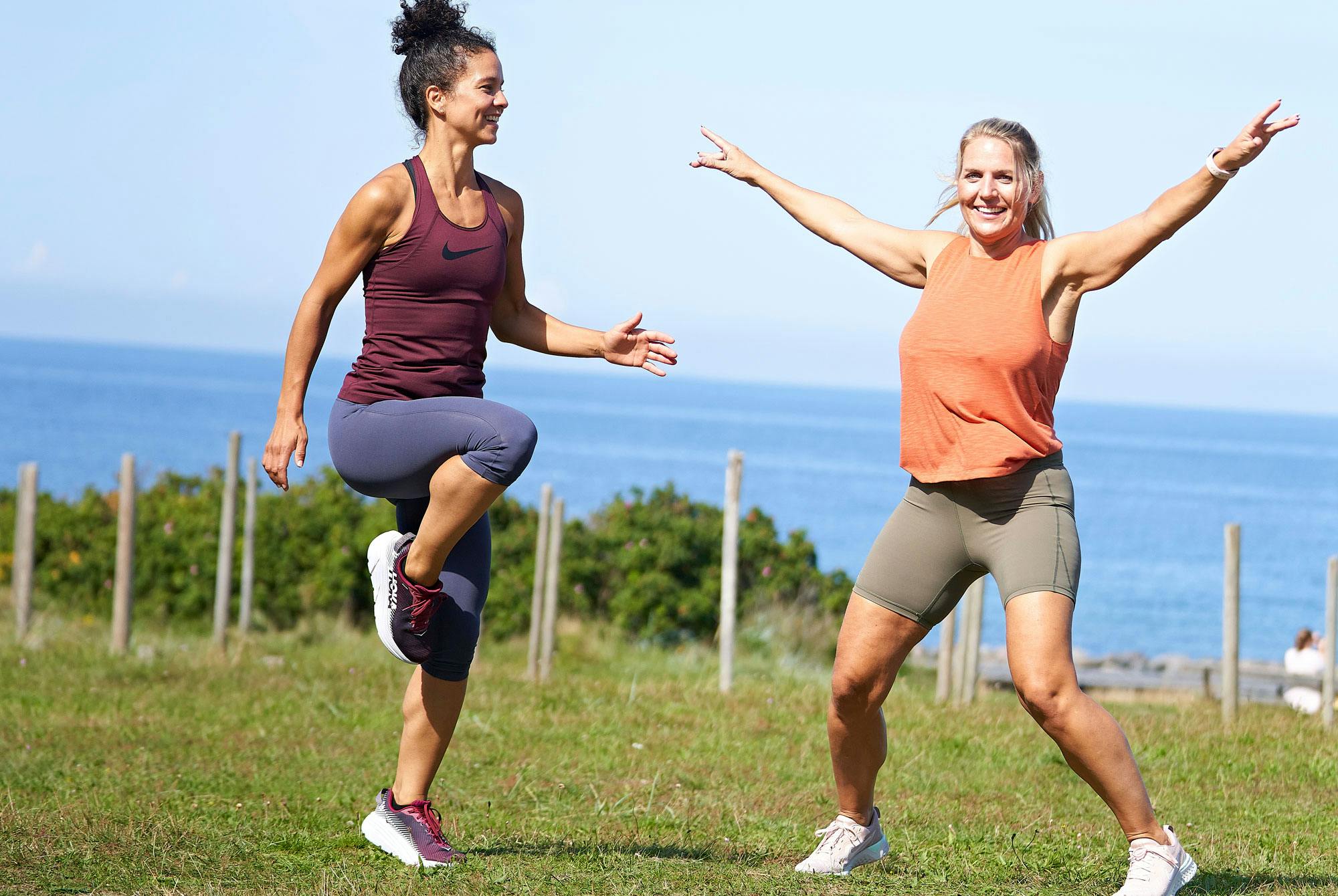 Två kvinnor tränar under semestern på en gräsmatta.